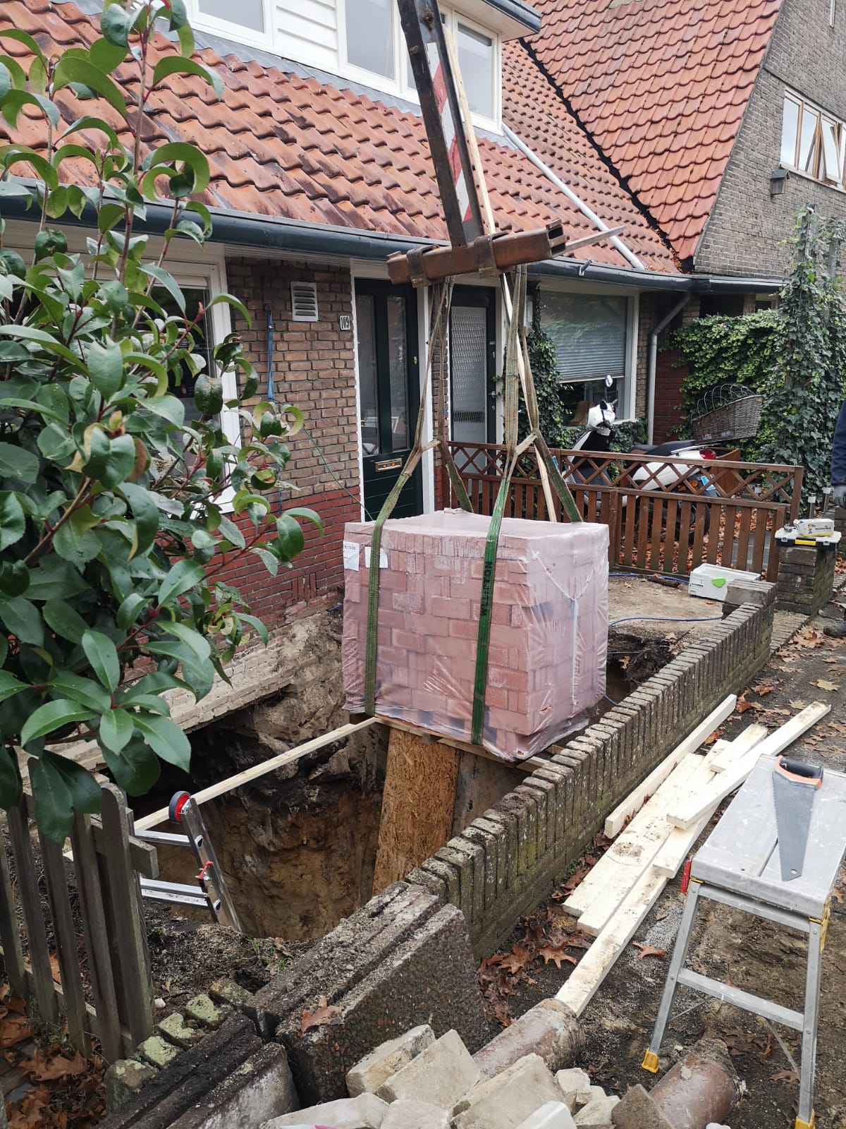 Pallet stenen wordt neergelaten in de bouwput