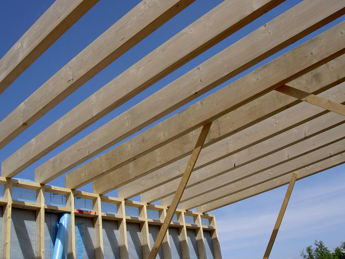 Nieuwe balklaag voor het dak, zichtbaar houtwerk tegen blauwe lucht